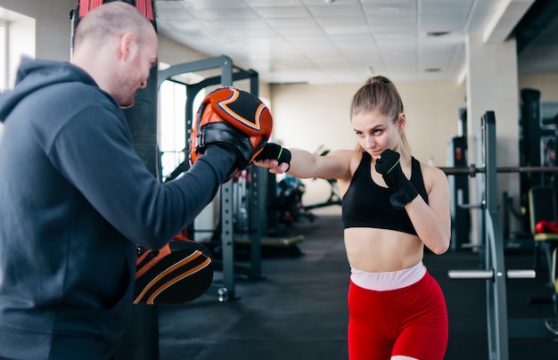 Fit blonde vrouw training punch met man trainer