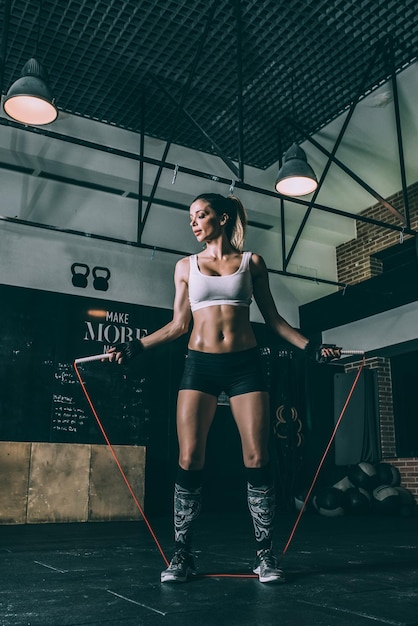 Fit blonde woman jumping rope training working out in Gym