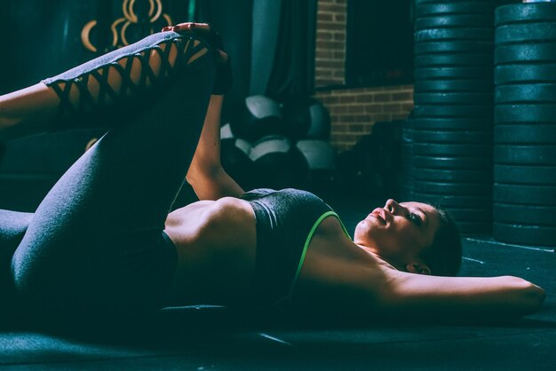 체육관에서 스트레칭과 크런치를 하는 바닥에 누워있는 금발의 여성