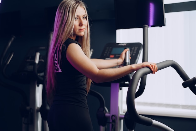 Fit bochtige jonge blonde vrouw training in een cardio-zone in een sportschool