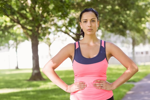 Fit brunette denken met haar handen op de heupen