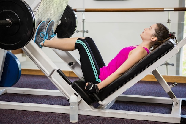 Fit brunette doing exercises for legs at the gym