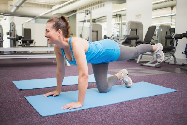 Fit brunette doing pilates on exercise mat