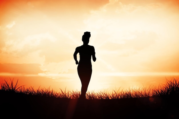 Photo fit brunette jogging away from camera against orange sunrise
