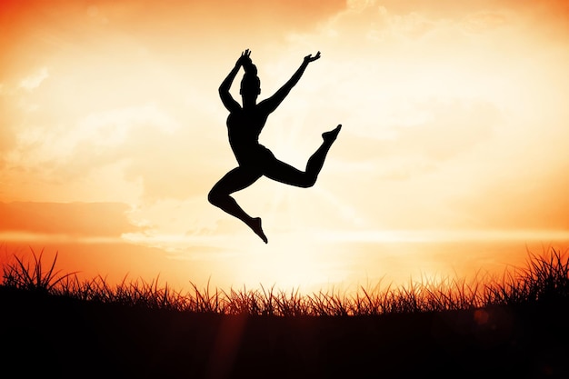 Photo fit brunette jumping and posing against orange sunrise