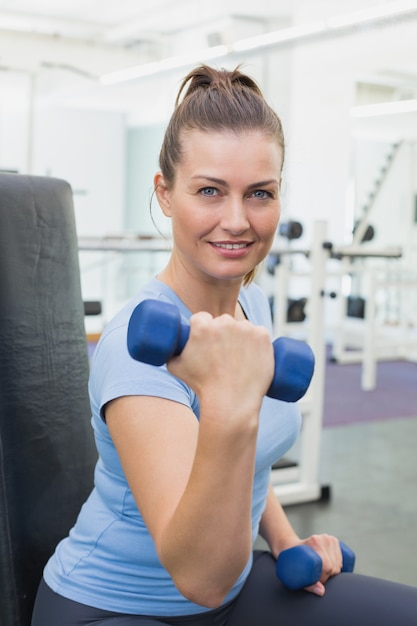 Fit brunette lifting blue dumbbells