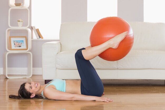 Fit brunette lifting exercise ball with legs