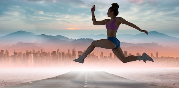 Fit brunette running and jumping against sun shining over road and city