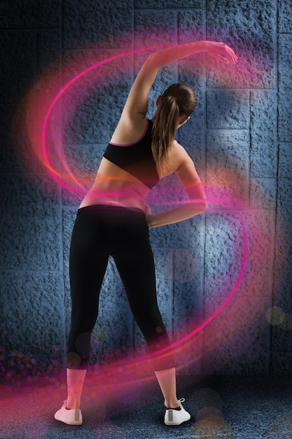 Fit brunette stretching rear view against dark grey room