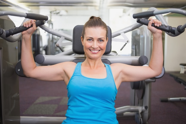 Fit brunette using weights machine for arms