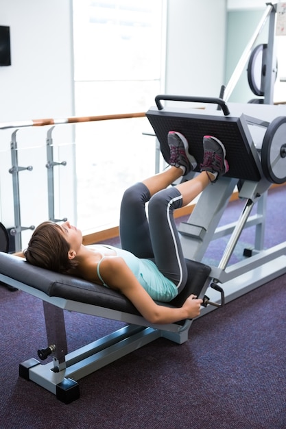 Fit brunette using weights machine for legs