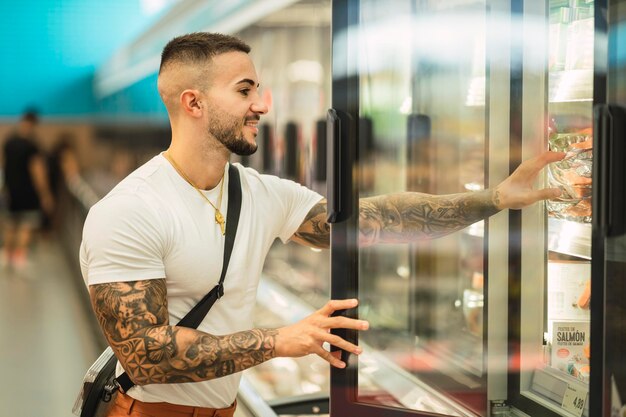 Fit Caucasian tattooed male athlete buying food at the store