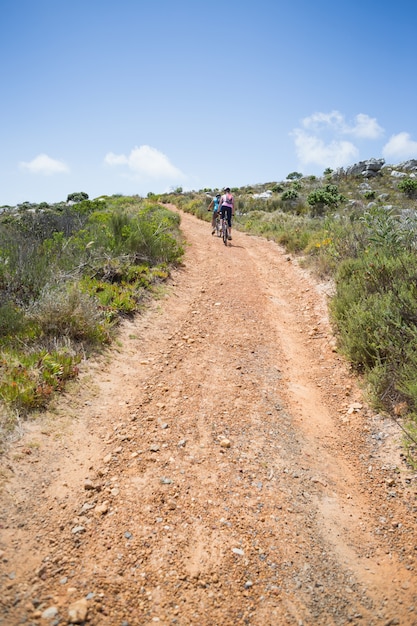 Fit couple cycling up mountain trail