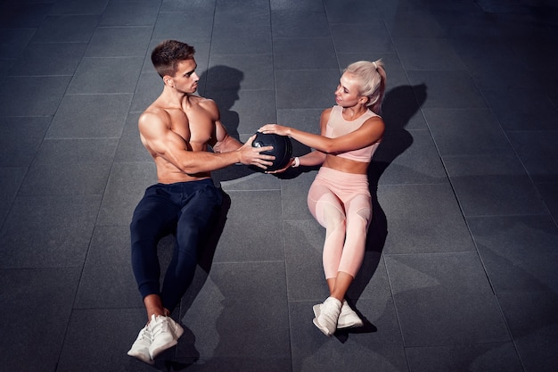 Fit couple doing abdominal ball exercise at gym.