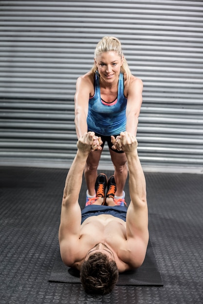 Fit couple exercising ttogether at gym