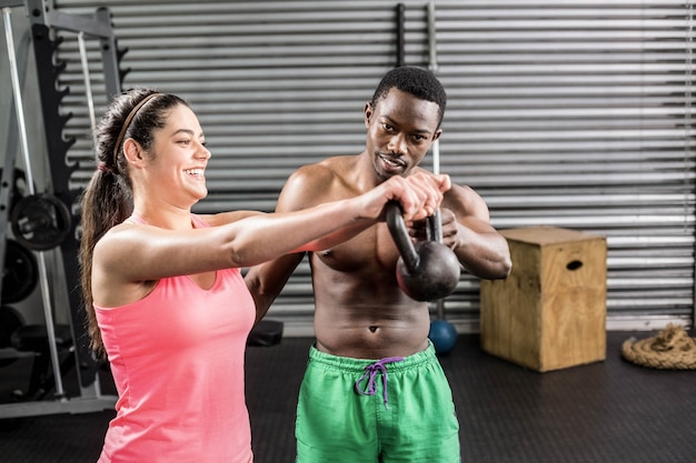 Fit couple lifting dumbbells at crossfit gym