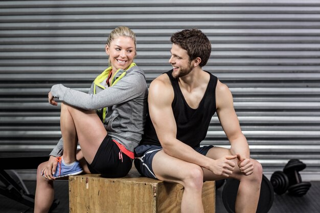 Fit couple smiling at each other at crossfit gym