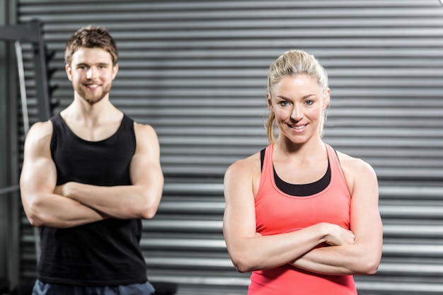 Fit couple with arm crossed at crossfit gym