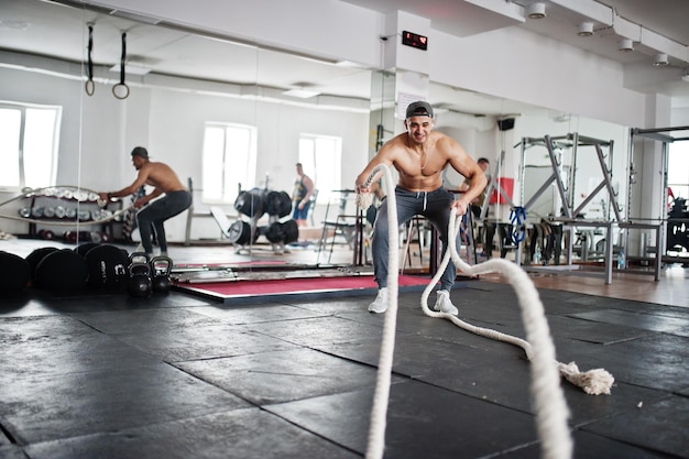 Fit en gespierde Arabische man aan het trainen met zware touwen in de sportschool