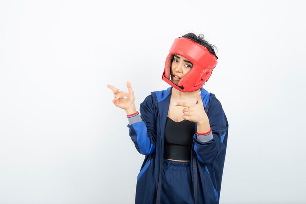 fit female boxer in red helmet standing over white.