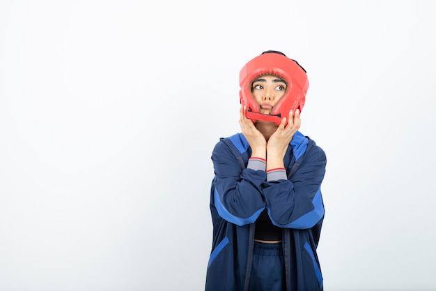 fit female boxer in red helmet standing over white.