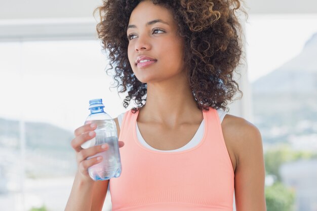 Fit female holding water bottle at gym