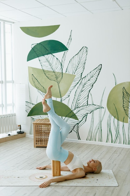 A fit female instructor trains on a yoga mat in a bright studio