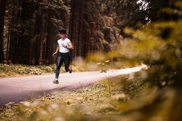 Fit female jogger training for cross country forest trail race in nature park Young female athlete jogging in mountains Runner doing morning physical training