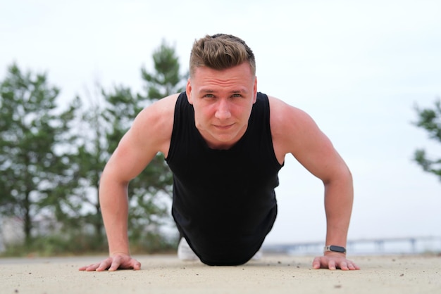 fit fitness man atleet atletische man doet push ups training oefening op de grond training buitenshuis