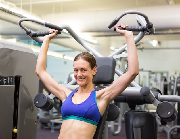 Fit gelukkig brunette met behulp van gewichten machine voor armen