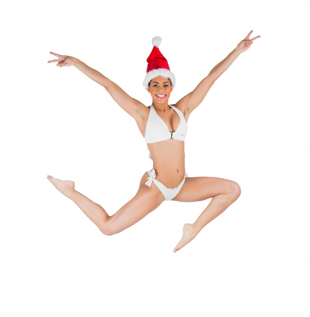 Fit girl in bikini smiling at camera wearing santa hat