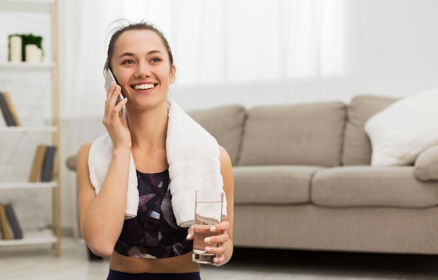 Fit girl talking on phone after exercising at home