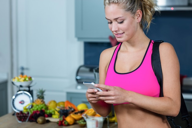 Foto ragazza adatta che manda un sms nella cucina