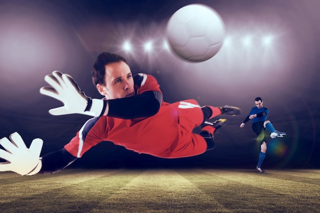 Photo fit goal keeper jumping up against football pitch under spotlights