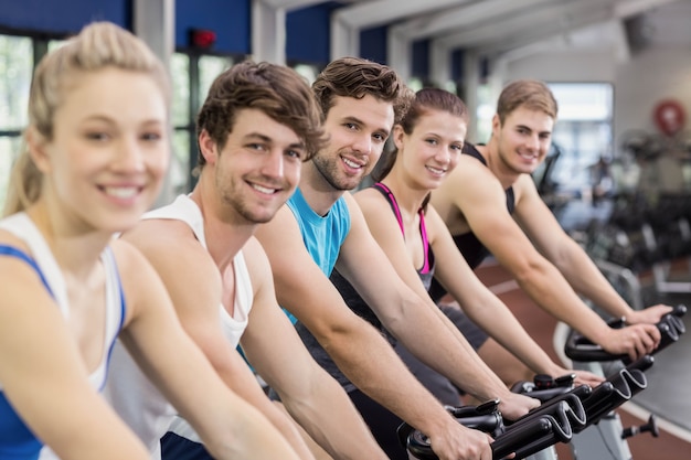 Fit group of people using exercise bike together in gym