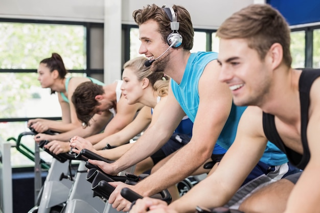 Fit group of people using exercise bike together at gym