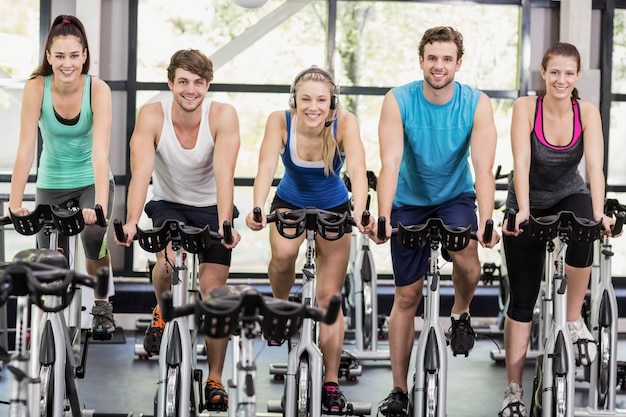 Fit group of people using exercise bike together at gym