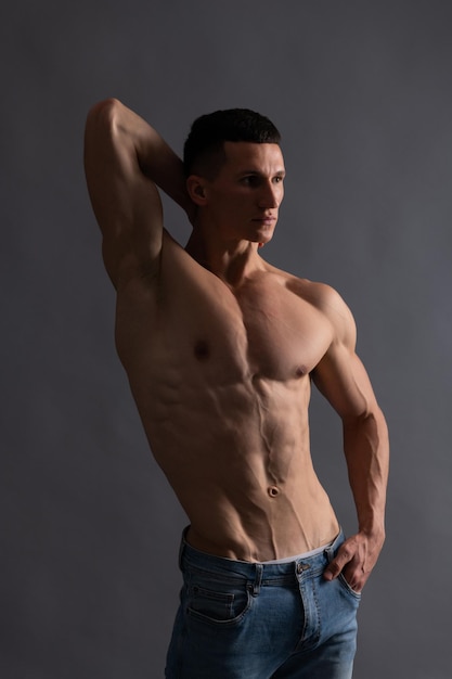 Fit guy with six pack abs torso pose shirtless grey background, muscle.