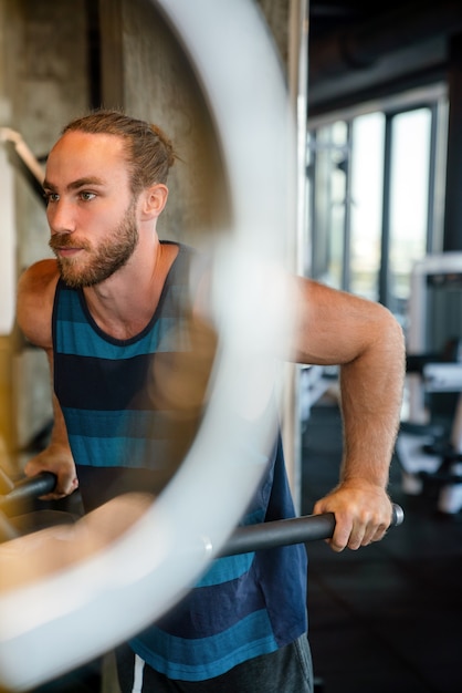 Photo fit handsome man exercising at the gym on a machine