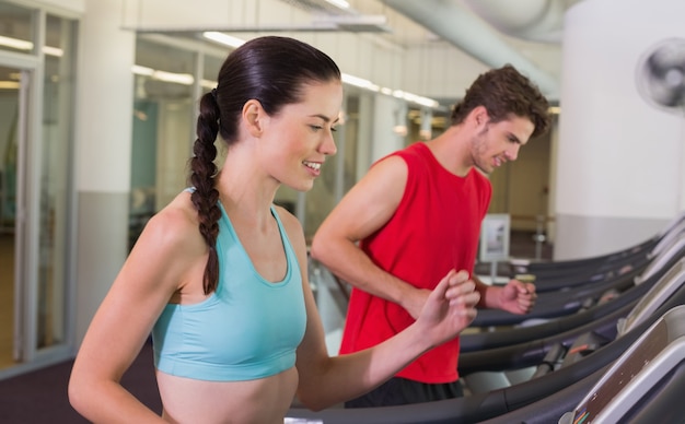 Fit happy couple running together on treadmills