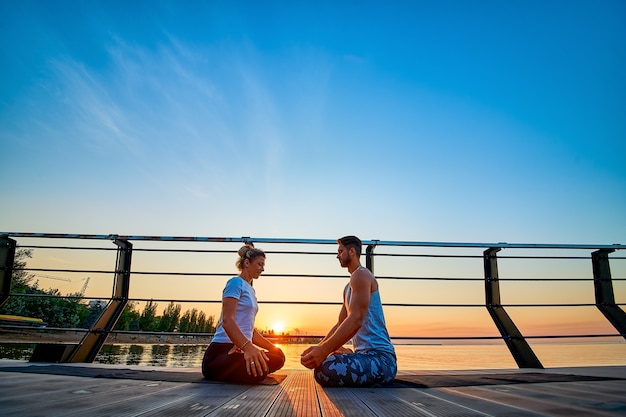 Fit jong stel doet yoga lotus pose gezonde levensstijl mensen buitensport activiteit op familie vac...