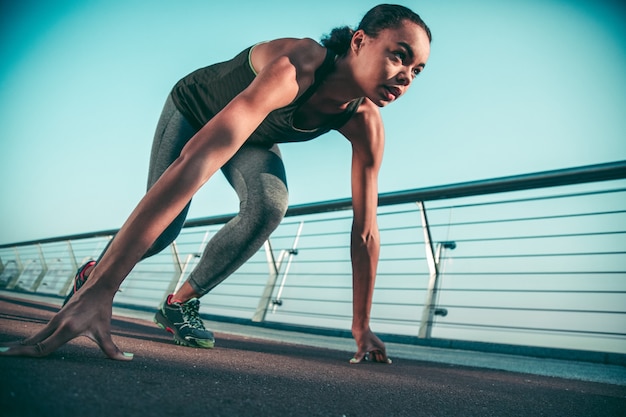 Fit jonge atleet bij de start tijdens haar training op de brug