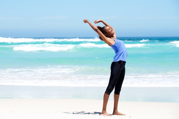 Fit jonge vrouw die zich uitstrekt op het strand