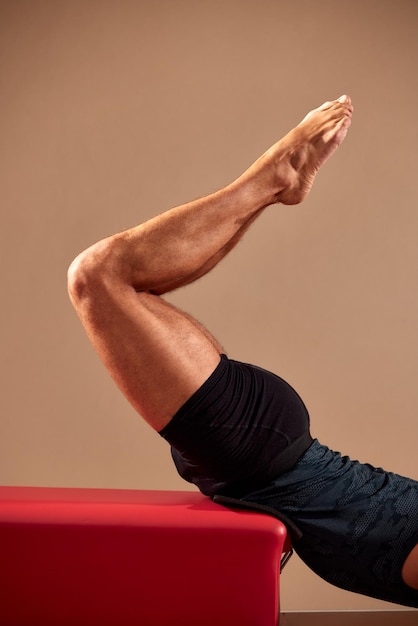 Fit man doet een lunge stretch yoga pilates oefening om zijn spieren te versterken en te versterken met behulp van een reformer in een sportschool