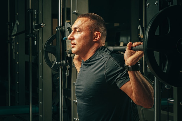 Fit man doet squats in een trainingsmachine