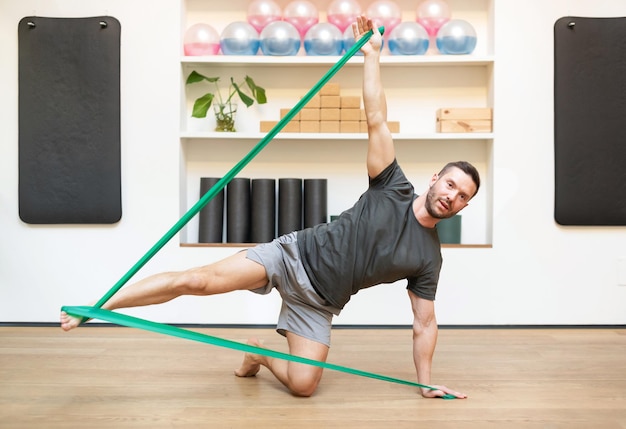 Fit man doing exercise with resistance band in fitness center