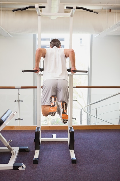 Fit man doing pull ups in fitness studio