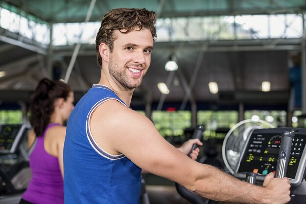 Fit man on elliptical bike at gym