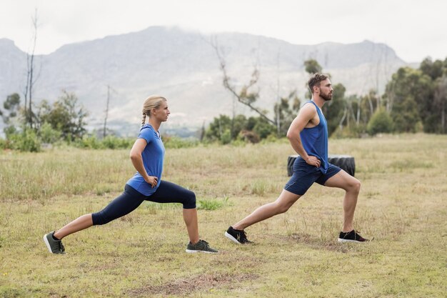 Fit man en vrouw trainen in bootcamp op een zonnige dag