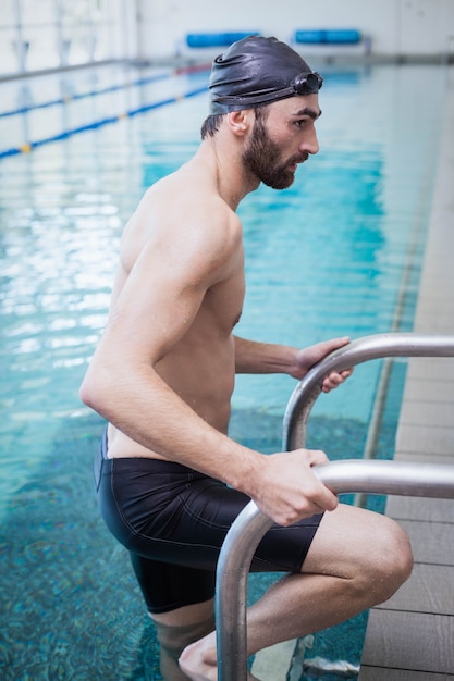 ぴったりの男性がプールで水から降りる